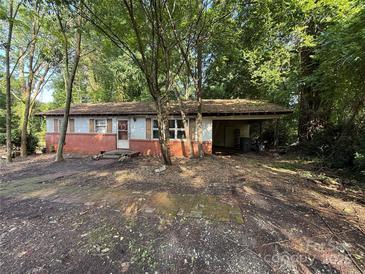 View of home's front exterior with brick accent, covered porch, and mature trees at 112 Greenwood Ave, Belmont, NC 28012