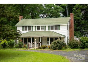 Charming two-story home with a green roof, brick chimney, and a welcoming front porch at 1612 Forum Ln, Iron Station, NC 28080