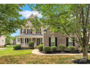 Charming two-story brick home featuring a welcoming front porch and well-manicured landscaping at 6718 Heritage Orchard Way, Huntersville, NC 28078