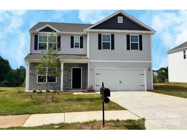 New two-story home featuring a two car garage, stone accents, and a well manicured lawn at 215 Lake George Dr, Shelby, NC 28152
