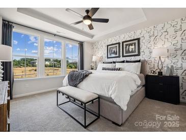 Bright main bedroom featuring three windows, a tray ceiling and a patterned accent wall at 3118 Stelfox St, Charlotte, NC 28262