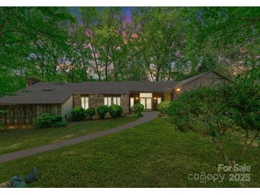 Evening view of wood and stone home, surrounded by trees and mature landscaping at 4417 Walter Nelson Rd, Mint Hill, NC 28227