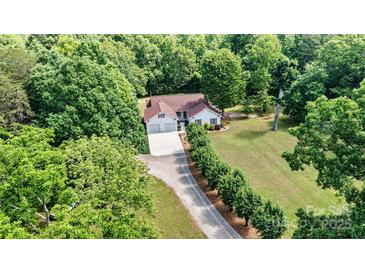A charming single-Gathering home with an attached two-car garage sits nestled among lush trees on a sprawling green lawn at 6992 Sherrills Ford Rd, Sherrills Ford, NC 28673
