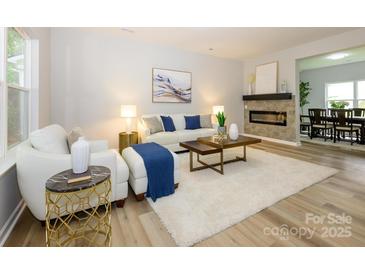 Bright living room featuring a stone fireplace, neutral decor, and wood-look flooring at 8611 Earthenware Dr, Charlotte, NC 28269