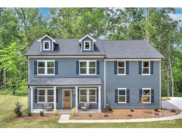 Charming two-story home with blue siding, dormer windows, and inviting front porch in a wooded setting at 1025 Harrogate Dr, Bessemer City, NC 28016