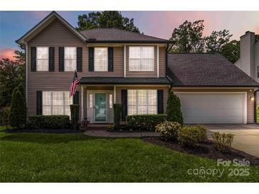 Two-story home featuring black shutters, an American flag, a well-manicured lawn, and a two-car garage at 204 Pebble Creek Xing, Fort Mill, SC 29715
