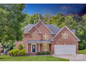 Beautiful two-story brick home with manicured lawn and mature trees under a dramatic sky at 3741 Tea Olive Rd, Gastonia, NC 28056