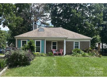 Charming brick home featuring a well-maintained lawn, colorful landscaping, and a cozy porch with two pink chairs at 7607 Swedish Ivy Ln, Charlotte, NC 28227