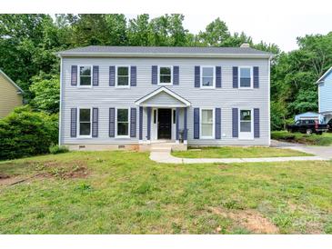 Charming two-story home with gray siding and blue shutters surrounded by a luscious green lawn at 1013 Doby Springs Dr, Charlotte, NC 28262