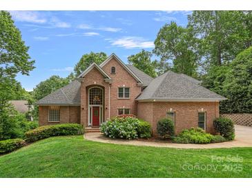 Charming red brick home featuring a manicured front yard and a vibrant red front door at 166 Pinnacle Shores Dr, Mooresville, NC 28117