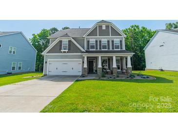 Charming two-story home with a manicured lawn, neutral siding, stone accents, and a welcoming front porch at 2714 Woodlands Creek Dr, Monroe, NC 28110