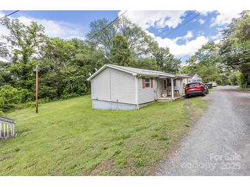 Quaint home featuring light siding, green lawn, and gravel driveway at 100 Lanier St, Mount Holly, NC 28120