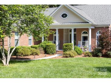 Charming brick home featuring a covered front porch with classic columns and beautifully manicured landscaping at 122 Waterford Dr, Mooresville, NC 28117