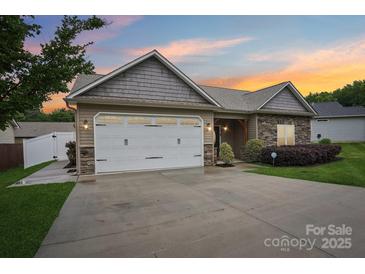 Charming home boasts a two-car garage, stone accents, manicured lawn, and inviting facade at dusk at 2021 Chantilly Ln, Salisbury, NC 28146