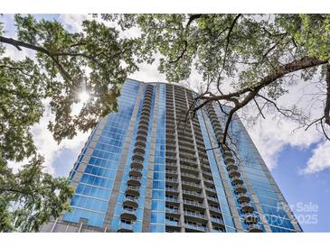 Striking building exterior showcases a modern design with glass windows and private balconies, framed by leafy trees at 210 N Church St # 2910, Charlotte, NC 28202