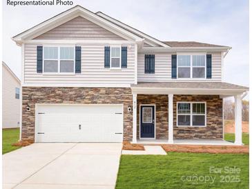 Charming two-story home featuring stone accents, blue shutters, a two-car garage, and a well-maintained lawn at 221 Paige Rd, Kings Mountain, NC 28086