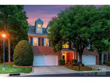 Charming red brick two-story home featuring a three-car garage and lush landscaping at 3128 Ethereal Ln, Charlotte, NC 28226