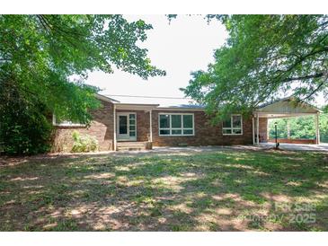 Charming brick home with mature trees and a covered carport offers a welcoming facade and ample outdoor space at 4268 Wilkesboro Hwy, Statesville, NC 28625