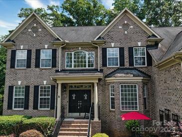 Charming brick two-story home featuring black shutters, arched windows and manicured landscaping at 9913 Hazelview Dr, Charlotte, NC 28277