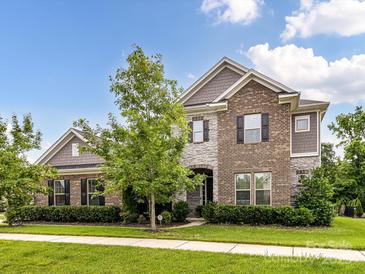 Charming brick and stone two-story home with manicured lawn and beautiful landscaping at 121 Enclave Meadows Ln, Matthews, NC 28104