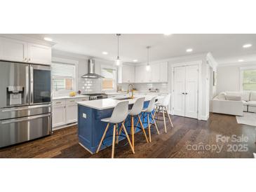 Modern kitchen featuring a large island with seating, stainless steel appliances, and hardwood floors at 1446 Downs Ave, Charlotte, NC 28205