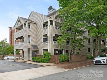Multi-story condo building with stacked covered patios and mature landscaping and brick retaining wall at 212 W 10Th St # 3, Charlotte, NC 28202
