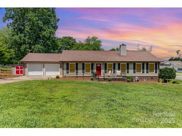 Charming single-story home with a well-manicured lawn, a red front door and a two-car garage at 2401 Hoffman St, Gastonia, NC 28054