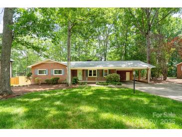 Charming brick home with a well-maintained lawn, mature trees, and covered carport at 403 Cherrywood Ln, Albemarle, NC 28001
