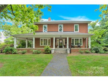 Charming two-story brick home featuring a welcoming front porch with classic columns and a beautifully landscaped yard at 634 E Center Ave, Mooresville, NC 28115