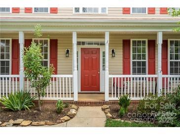 Charming front porch with red door, white railing and columns, and manicured landscaping at 6614 Truman St, Indian Trail, NC 28079