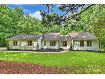 Charming single-story home featuring lush green lawn, mature trees, and a manicured landscape at 9520 Squirrel Hollow Ln, Charlotte, NC 28270