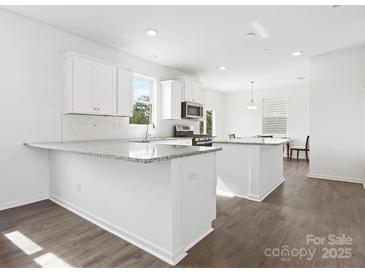 Bright kitchen featuring white cabinets, granite countertops, stainless steel appliances, and an island with a breakfast bar at 1433 Harleston St, Indian Trail, NC 28079