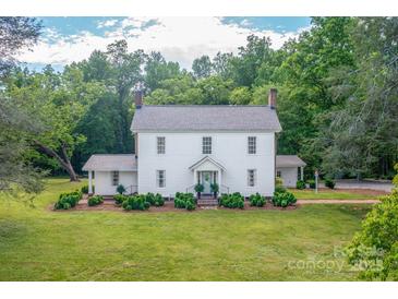 Charming two-story white home with lush green lawn and mature trees, creating a serene and inviting setting at 1567 Jennings Rd, Statesville, NC 28625