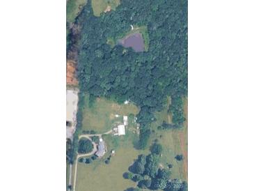An aerial view of a sprawling property featuring lush greenery, a serene pond, and multiple buildings at 269 Johnson Dairy Rd, Mooresville, NC 28115