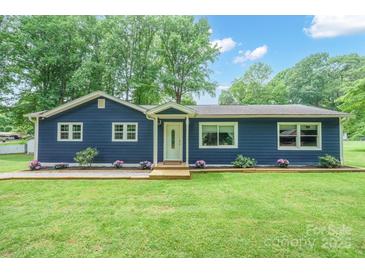 Charming blue home featuring a well-maintained yard and appealing landscaping at 327 Holly Dr, Mount Holly, NC 28120