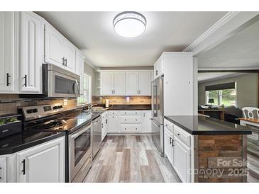 Bright kitchen featuring white cabinets, stainless steel appliances, and modern countertops and backsplash at 327 Holly Dr, Mount Holly, NC 28120
