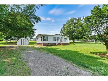 Charming single-story home with green shutters, a lush lawn, storage shed, and gravel driveway at 338 Hickory Grove Rd, Harmony, NC 28634