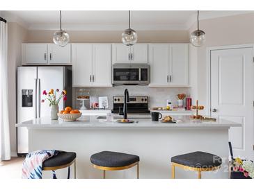 Bright, modern kitchen featuring white cabinetry, stainless steel appliances, and a large island with seating at 4110 Lattistep Ln, Charlotte, NC 28269