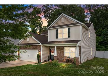 Charming two-story home featuring stone accents, a cozy front porch, and well-manicured lawn at 413 Wheat Field Dr, Mount Holly, NC 28120