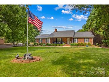 Charming brick home with well-manicured lawn, mature trees, and inviting front porch at 648 Odell School Rd, Concord, NC 28027