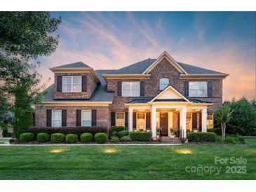 Charming two-story brick home featuring a welcoming front porch and manicured landscaping at 8301 Caesars Head Dr, Waxhaw, NC 28173