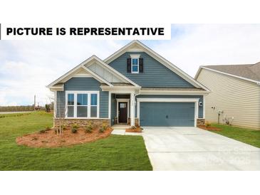Charming single-story home featuring blue siding, a two-car garage, and a well-manicured lawn at 124 S Shayna Rd, Troutman, NC 28166