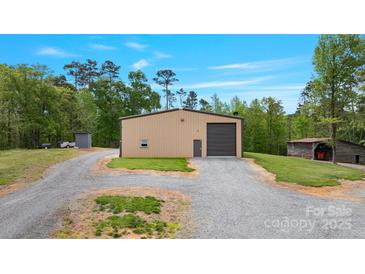 Exterior view of a metal building featuring a large garage door and gravel driveway at 10016 Morgan Mill Rd, Monroe, NC 28110