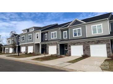 View of newly built townhomes showcasing stone accents, garage doors, and neutral siding in a suburban neighborhood at 2541 Ruby Dixon Crossing Dr # 18, Gastonia, NC 28056