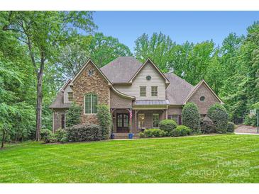 Beautiful brick and stone two-story home with mature trees and lush landscaping on a well-manicured lawn at 1056 James Madison Dr, Matthews, NC 28104