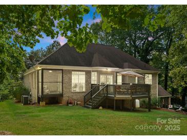 Expansive rear exterior showcasing a charming deck, screened-in porch, and well-manicured lawn at 171 Secretariat Dr, Mooresville, NC 28117