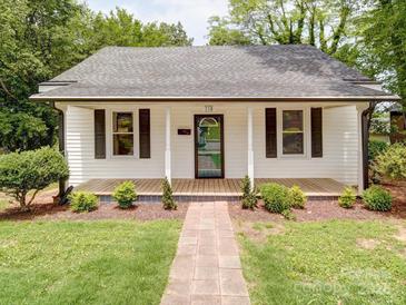 Charming home with a welcoming front porch, beautiful landscaping, and a brick walkway to the front door at 318 Chestnut Ave, Kannapolis, NC 28081