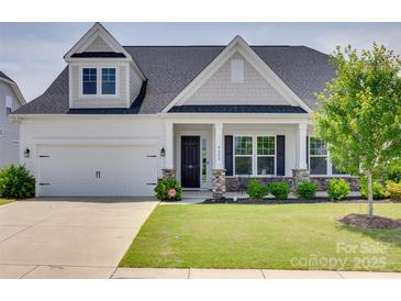 Charming home featuring a well-manicured lawn, white siding, stone accents, and a covered front porch at 4689 Kingswood Dr, Indian Land, SC 29707