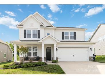 Charming two-story home featuring a well-manicured lawn, a covered porch, and a two car attached garage at 5121 Ennisworth Ln, Charlotte, NC 28214