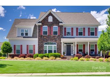 Charming two-story home with a combination of stone and siding and a well-manicured lawn at 8493 Twickenham Ter, Harrisburg, NC 28075